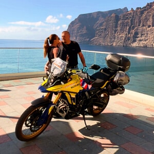 Two motorcyclists ride alongside a yellow Suzuki V-Strom 800 in Los Gigantes, Tenerife.